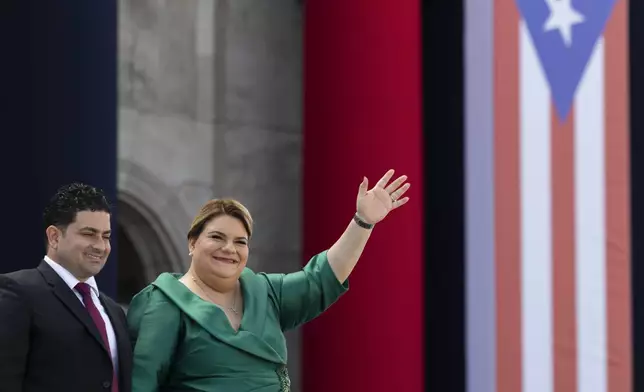 Jenniffer Gonzalez Colon waves alongside her husband Jose Yovin Vargas during her swearing-in ceremony as governor outside the Capitol in San Juan, Puerto Rico, Thursday, Jan. 2, 2025. (AP Photo/Alejandro Granadillo)