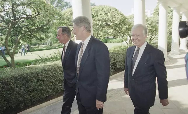 FILE - U.S. President Bill Clinton, flanked by former Presidents George Bush, left, and Jimmy Carter, walks through the Colonnades of the White House, Washington, on Sept. 13, 1993. (AP Photo/Wilfredo Lee, File)