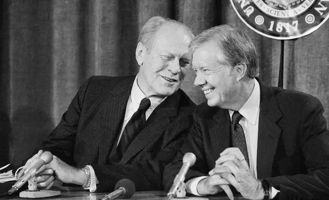 FILE - Former Presidents Gerald Ford and Jimmy Carter share a light moment as they take a break from their Symposium on New Weapons Technologies and Soviet-American Relations at the University of Michigan to talk with reporters on Nov. 14, 1984, in Ann Arbor, Mich. (AP Photo/Rob Kozloff, File)