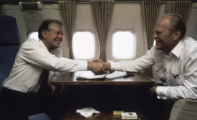 FILE - President Jimmy Carter is seen with former President Gerald Ford aboard Air Force 1 between Cairo and Spain on Oct. 10, 1981. (AP Photo/Dirck Halstead, File)