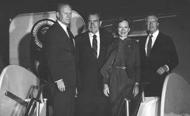 FILE - Former presidents Gerald Ford, Richard Nixon and Jimmy Carter, and former first lady Rosalynn Carter stand atop the ramp to an Air Force jet on Oct. 8, 1981, at Andrews Air Force Base, Md., just before their departure to attend the funeral in Cairo for slain Egyptian President Anwar Sadat. (AP Photo/John Duricka, File)