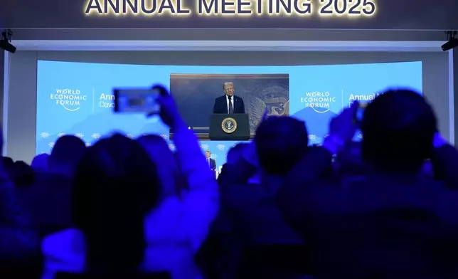 People follow a virtual speech of U.S. president Donald Trump at the Annual Meeting of World Economic Forum in Davos, Switzerland, Thursday, Jan. 23, 2025. (AP Photo/Markus Schreiber)