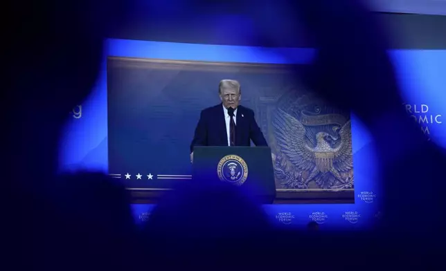 People follow a virtual speech of U.S. president Donald Trump at the Annual Meeting of World Economic Forum in Davos, Switzerland, Thursday, Jan. 23, 2025. (AP Photo/Markus Schreiber)