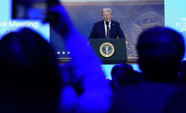 People follow a virtual speech of U.S. president Donald Trump at the Annual Meeting of World Economic Forum in Davos, Switzerland, Thursday, Jan. 23, 2025. (AP Photo/Markus Schreiber)