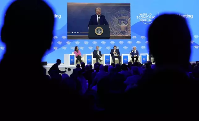 People follow a virtual speech of U.S. president Donald Trump at the Annual Meeting of World Economic Forum in Davos, Switzerland, Thursday, Jan. 23, 2025. (AP Photo/Markus Schreiber)