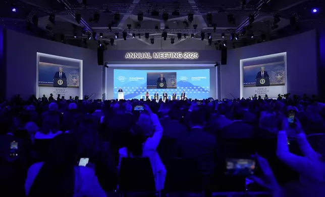 People follow a virtual speech of U.S. president Donald Trump at the Annual Meeting of World Economic Forum in Davos, Switzerland, Thursday, Jan. 23, 2025. (AP Photo/Markus Schreiber)