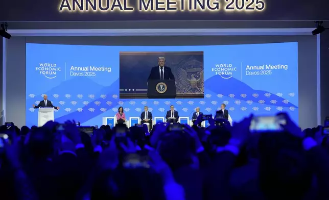 People follow a virtual speech of U.S. president Donald Trump at the Annual Meeting of World Economic Forum in Davos, Switzerland, Thursday, Jan. 23, 2025. (AP Photo/Markus Schreiber)