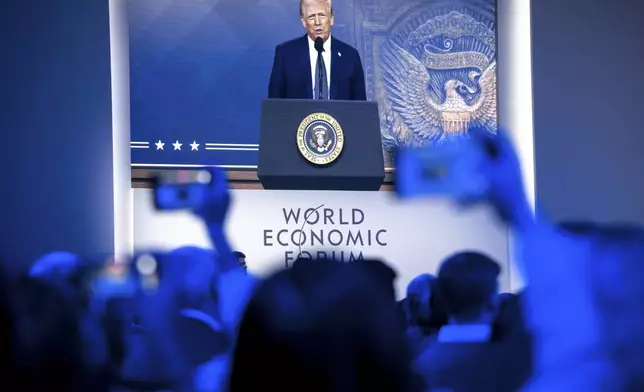 US President Donald J. Trump is shown on screens as he addresses via remote connection a plenary session in the Congress Hall, during the 55th annual meeting of the World Economic Forum (WEF), in Davos, Switzerland, Thursday, Jan. 23, 2025. (Laurent Gillieron/Keystone via AP)