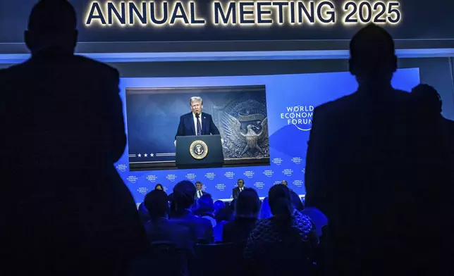US President Donald J. Trump is shown on screens as he addresses via remote connection a plenary session in the Congress Hall, during the 55th annual meeting of the World Economic Forum (WEF), in Davos, Switzerland, Thursday, Jan. 23, 2025. (Michael Buholzer/Keystone via AP)