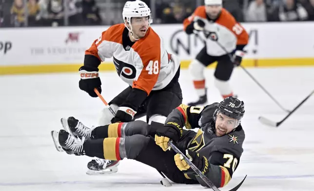 Vegas Golden Knights left wing Tanner Pearson (70) falls to the ice after passing the puck against Philadelphia Flyers center Morgan Frost (48) during the first period of an NHL hockey game Thursday, Jan. 2, 2025, in Las Vegas. (AP Photo/David Becker)