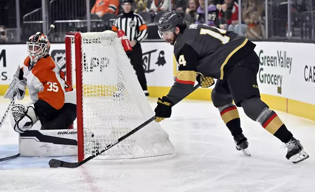 Vegas Golden Knights defenseman Nicolas Hague (14) scores with a wrap-around goal against Philadelphia Flyers goaltender Aleksei Kolosov (35) during the second period of an NHL hockey game Thursday, Jan. 2, 2025, in Las Vegas. (AP Photo/David Becker)