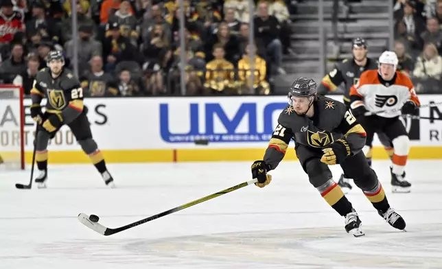 Vegas Golden Knights center Brett Howden (21) reaches for the puck during the second period of an NHL hockey game against the Philadelphia Flyers Thursday, Jan. 2, 2025, in Las Vegas. (AP Photo/David Becker)