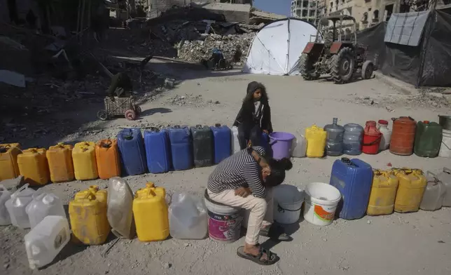 Palestinian children wait next to a row of jerrycans to collect water in Beit Lahia, northern Gaza Strip, Wednesday, Jan. 29, 2025, after Israel began allowing hundreds of thousands of Palestinians to return to the heavily damaged area last Monday. (AP Photo/Jehad Alshrafi)