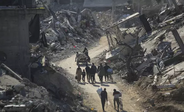 Palestinians who have returned walk among the rubble of buildings largely destroyed by Israeli army bombardments in Beit Lahia, northern Gaza Strip, Wednesday, Jan. 29, 2025, after Israel began allowing hundreds of thousands of Palestinians to return to the heavily damaged area last Monday.(AP Photo/Jehad Alshrafi)