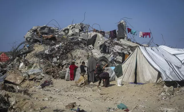 A Palestinian family sits outside a tent next to their destroyed house in Beit Lahia, northern Gaza Strip, Wednesday, Jan. 29, 2025, after Israel began allowing hundreds of thousands of Palestinians to return to the heavily damaged area last Monday. (AP Photo/Jehad Alshrafi)