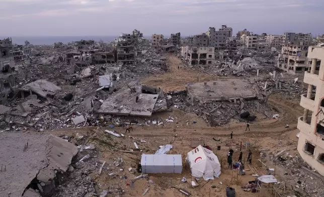 Palestinians stand next to tents surrounded by buildings that were destroyed by the Israeli air and ground offensive are seen at the Tel al-Hawa neighbourhood in Gaza Strip, Tuesday, Jan. 28, 2025. (AP Photo/Mohamamd Abu Samra)