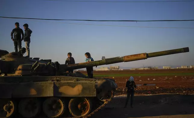 Children on the top of an ousted Syrian government forces tank that was left on a street in the town of Marea on the outskirts of Aleppo city, Syria, Tuesday, Jan. 28, 2025. (AP Photo/Khalil Hamra)