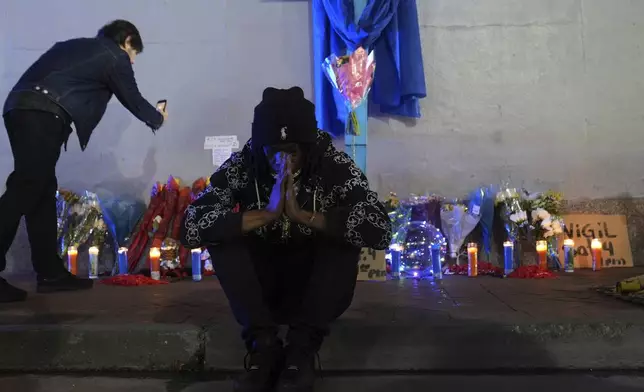 Sav Bennly sits in front of a memorial at Bourbon and Canal Street in the French Quarter, Thursday, Jan. 2, 2025 in New Orleans. (AP Photo/George Walker IV)