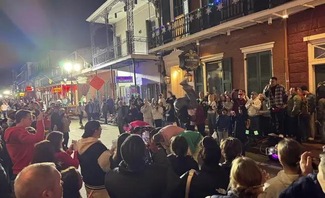 A street performer flips over a line of people on Bourbon street, Thursday, Jan. 2, 2025, after the area reopened to the public following a deadly attack in New Orleans. (AP Photo/Jack Brook)