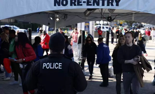 Police watch as fans walk through security checkpoints outside Caesars Superdome ahead of the Sugar Bowl NCAA College Football Playoff game, Thursday, Jan. 2, 2025, in New Orleans. (AP Photo/Butch Dill)