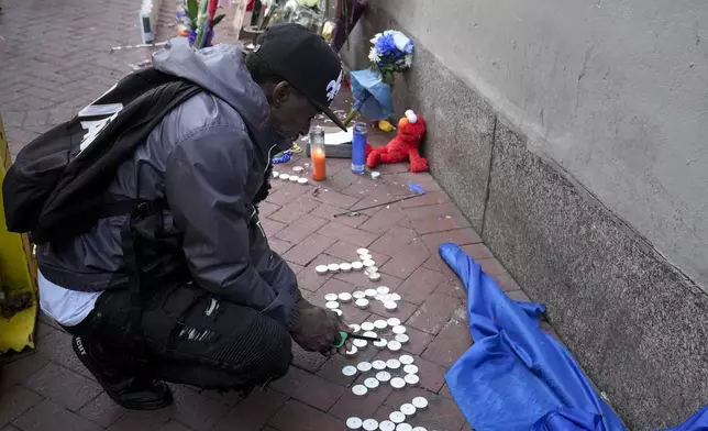 Eddie Williams lights candles for his uncle, who was killed in a deadly truck attack, at a memorial to the victims on Bourbon Street in the French Quarter, Friday, Jan. 3, 2025, in New Orleans. (AP Photo/George Walker IV)