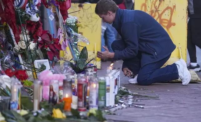 Nathan Williams, a University of New Orleans student, lights a candle at memorial on Bourbon Street for the victims of a deadly truck attack on New Year's Day in New Orleans, Friday, Jan. 3, 2025. (AP Photo/Gerald Herbert)