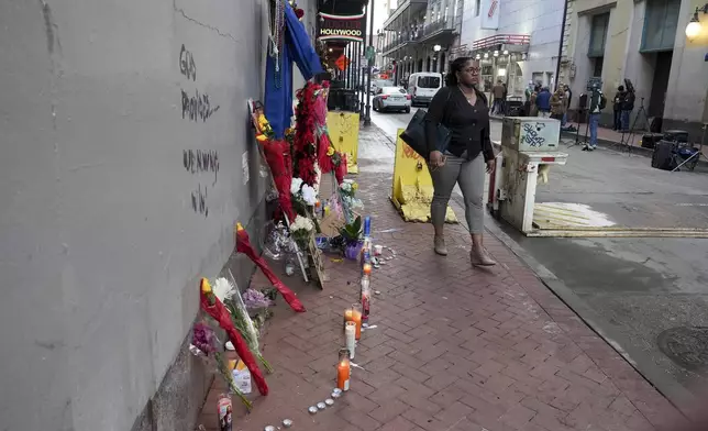 A woman walks past a memorial to the victims of a deadly truck attack on Bourbon Street in the French Quarter, Friday, Jan. 3, 2025, in New Orleans. (AP Photo/George Walker IV)