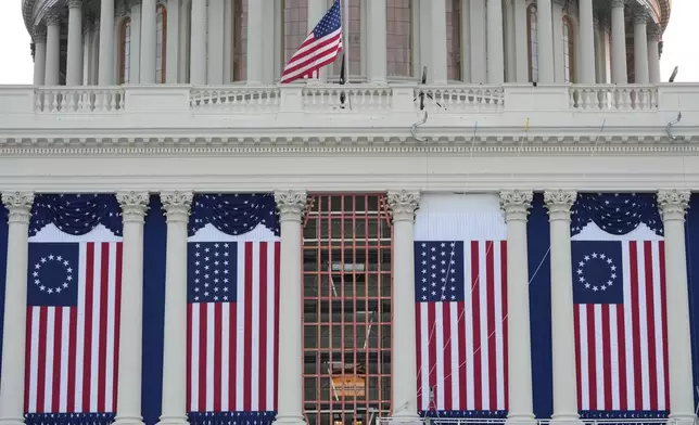 Flags hang in place on the West Front of the U.S. Capitol ahead of President-elect Donald Trump's upcoming inauguration, Sunday, Jan. 12, 2025, in Washington. (AP Photo/Jon Elswick)