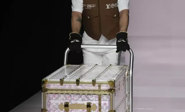 A man presents a suitcase as part of the men's Louis Vuitton Fall-Winter 2025-2026 collection, that was presented in Paris, Tuesday, Jan. 21, 2025. (AP Photo/Michel Euler)