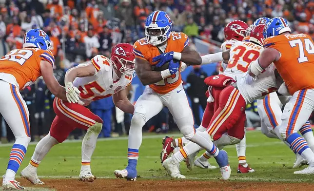 Denver Broncos running back Audric Estime (23) scores past Kansas City Chiefs linebacker Leo Chenal (54) during the second half of an NFL football game Sunday, Jan. 5, 2025, in Denver. (AP Photo/David Zalubowski)