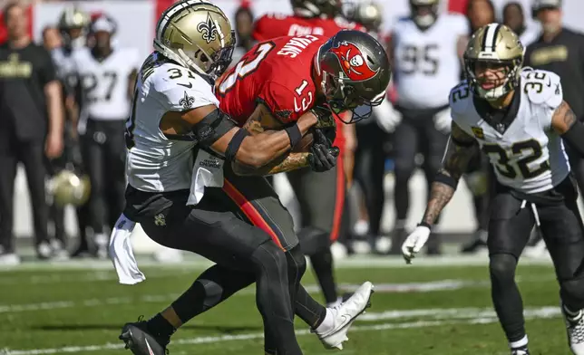 Tampa Bay Buccaneers wide receiver Mike Evans (13) is brought down by New Orleans Saints safety Jordan Howden (31) during the first half of an NFL football game Sunday, Jan. 5, 2025, in Tampa, Fla. (AP Photo/Jason Behnken)