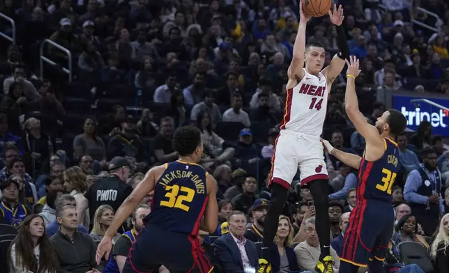 Miami Heat guard Tyler Herro (14) passes while defended by Golden State Warriors guard Stephen Curry, right, during the first half of an NBA basketball game Tuesday, Jan. 7, 2025, in San Francisco. (AP Photo/Godofredo A. Vásquez)