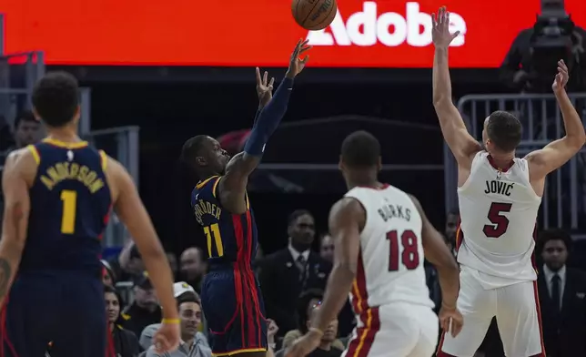 Golden State Warriors guard Dennis Schröder, second from left, shoots a 3-point basket over Miami Heat forward Nikola Jovic (5) during the first half of an NBA basketball game Tuesday, Jan. 7, 2025, in San Francisco. (AP Photo/Godofredo A. Vásquez)