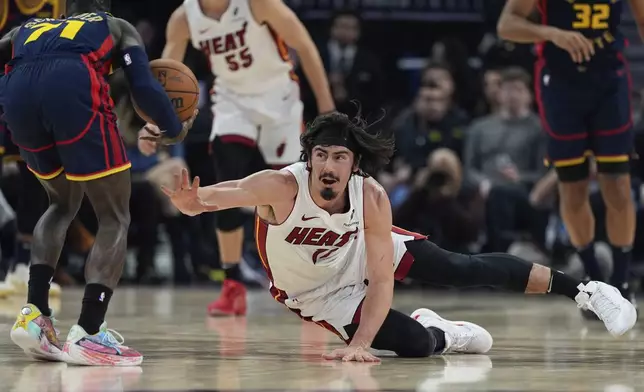 Miami Heat forward Jaime Jaquez Jr., center, dives as Golden State Warriors guard Dennis Schröder, left, recovers the loose ball during the first half of an NBA basketball game Tuesday, Jan. 7, 2025, in San Francisco. (AP Photo/Godofredo A. Vásquez)