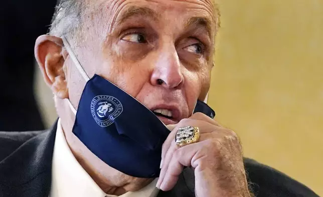 FILE — Former New York Mayor Rudy Giuliani, wearing a New York Yankees championship ring, pulls his face mask down to speak to an aide during a press conference at the Women's Republican Club, Sept. 16, 2020, in New York. (AP Photo/Kathy Willens, File)