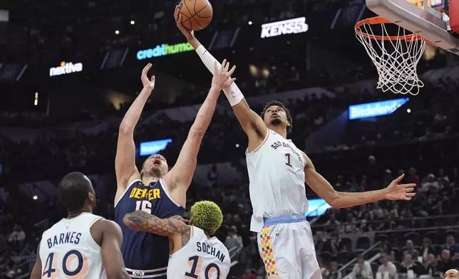 San Antonio Spurs center Victor Wembanyama (1) grabs a rebound over Denver Nuggets center Nikola Jokic (15) during the first half of an NBA basketball game in San Antonio, Saturday, Jan. 4, 2025. (AP Photo/Eric Gay)