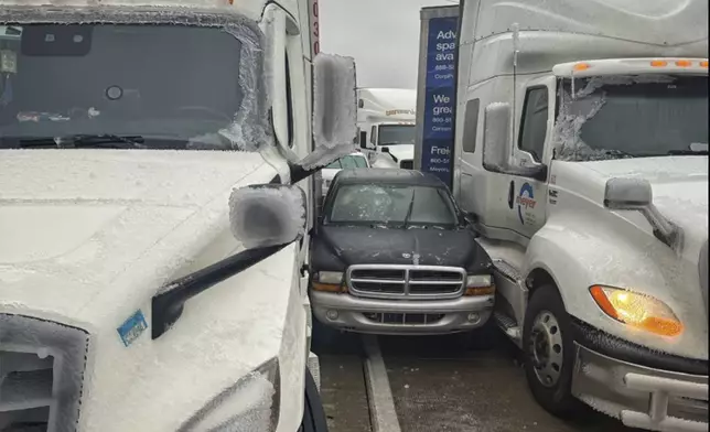 In a photo released by the Kansas Highway Patrol, a car is wedged between two trucks during icy weather Saturday, Jan. 4, 2024, in Salina, Kansas. (Kansas Highway Patrol via AP)