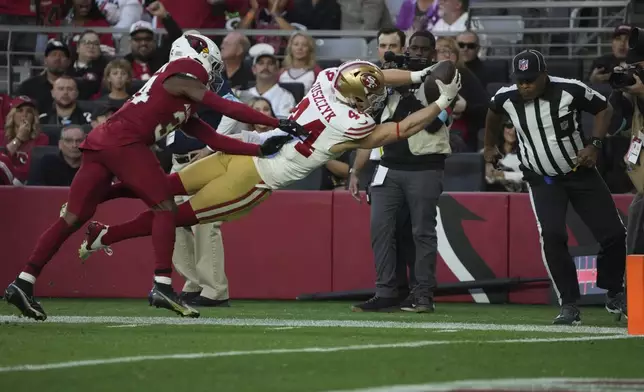 San Francisco 49ers fullback Kyle Juszczyk (44) dives into the end zone past Arizona Cardinals safety Jalen Thompson (34) for a touchdown during the second half of an NFL football game in Glendale, Ariz., Sunday, Jan. 5, 2025. (AP Photo/Rick Scuteri)