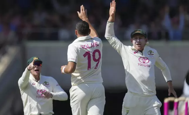 Australia's Scott Boland is congratulated by teammates Marnus Labuschagne, right, and Steve Smith after dismissing India's Yashasvi Jaiswal during play on the second day of the fifth cricket test between India and Australia at the Sydney Cricket Ground, in Sydney, Australia, Saturday, Jan. 4, 2025. (AP Photo/Mark Baker)