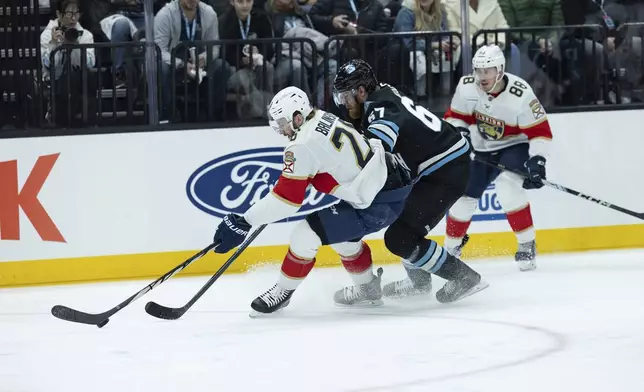 Florida Panthers defenseman Uvis Balinskis (26) fights for the puck against Utah Hockey Club left wing Lawson Crouse (67)during the first period of an NHL hockey game, Wednesday, Jan. 8, 2025, in Salt Lake City. (AP Photo/Melissa Majchrzak)