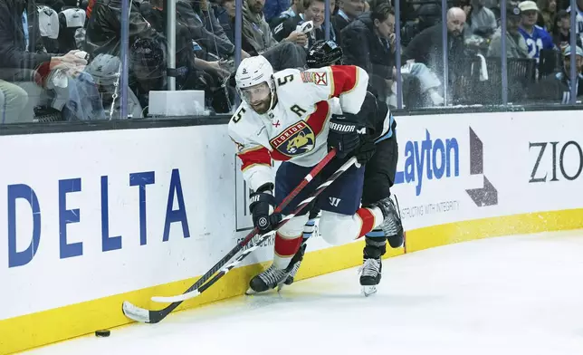 Florida Panthers defenseman Aaron Ekblad (5) fights for the puck against Utah Hockey Club center Nick Schmaltz (8) during the first period of an NHL hockey game, Wednesday, Jan. 8, 2025, in Salt Lake City. (AP Photo/Melissa Majchrzak)