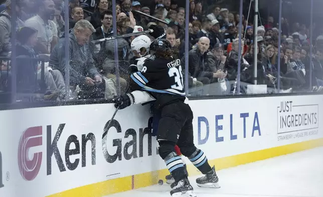 Utah Hockey Club center Liam O'Brien (38) slams Florida Panthers defenseman Dmitry Kulikov (7) into the boards going after the puck during the first period of an NHL hockey game, Wednesday, Jan. 8, 2025, in Salt Lake City. (AP Photo/Melissa Majchrzak)