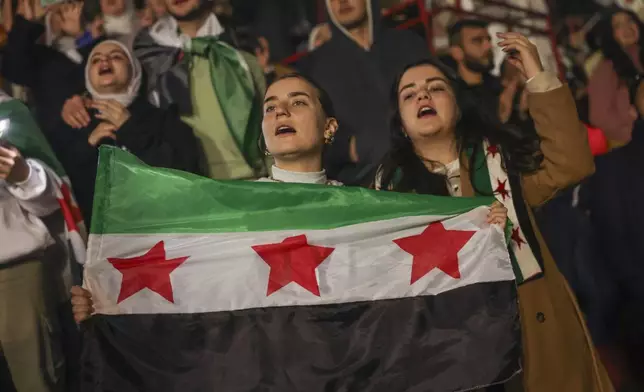 Syrians sing and hold a post-Assad flag during a concert by the recently returned "revolutionary" singer Wasfi Maasrani in Damascus late Wednesday Jan. 8, 2025..(AP Photo/Ghaith Alsayed)