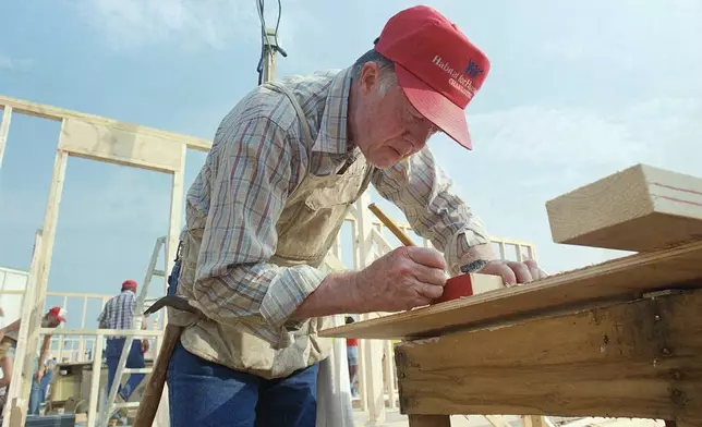 Former Pres. Jimmy Carter marks a board to be cut as he works with the Habitat for Humanity project in Charlotte, N.C., on Monday, July 27, 1987. The group of workers plans to build 14 homes in five days. (AP Photo/Mark Humphrey)