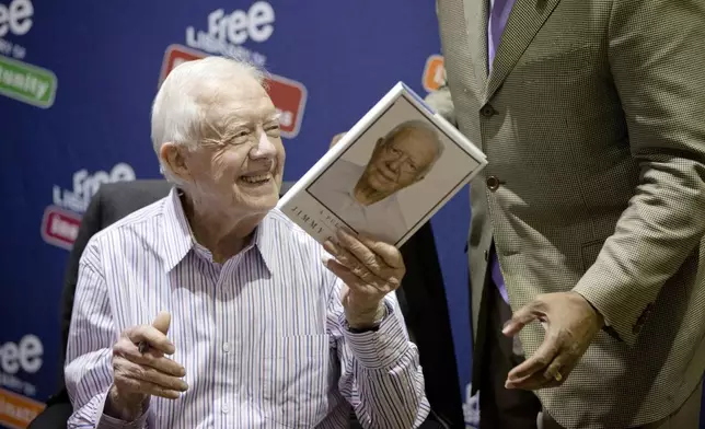 FILE - Former President Jimmy Carter hands a copy of his new book, "A Full Life: Reflections at Ninety," to Philadelphia Mayor Michael Nutter, on July 10, 2015, at the Free Library in Philadelphia. (AP Photo/Matt Rourke, File)