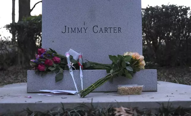 Bouquets of flowers and peanuts are placed at the base of a bust of former President Jimmy Carter at the Jimmy Carter Presidential Library and Museum Sunday, Dec. 29, 2024, in Atlanta. (AP Photo/Brynn Anderson)