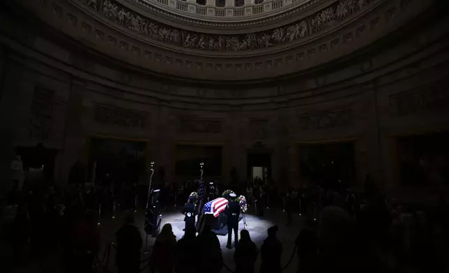 A spotlight iluminates the flag-draped casket to pay tribute toformer President Jimmy Carter as he lies in state at the Rotunda of the U.S. Capitol on Tuesday, Jan. 7, 2025, in Washington. (AP Photo/John McDonnell)