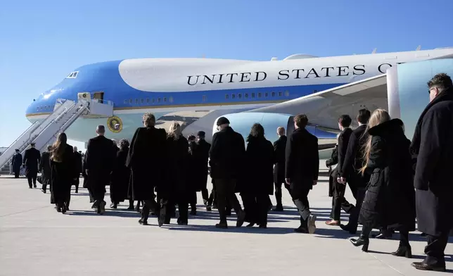 Family members walk to board the plane after the flag-draped casket of former President Jimmy Carter was placed on Special Air Mission 39 at Dobbins Air Reserve Base in Marietta, Ga., Tuesday, Jan. 7, 2025. Carter died Dec. 29 at the age of 100. (AP Photo/Alex Brandon, Pool)