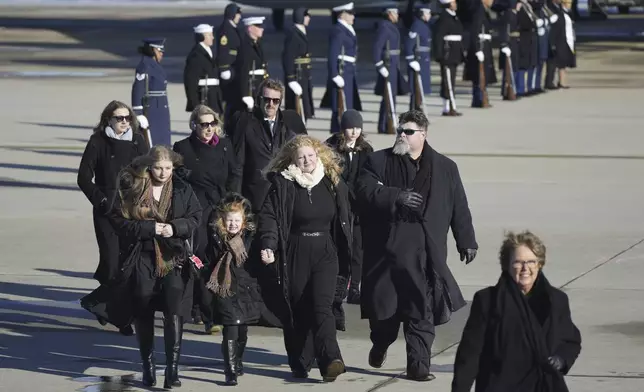 The Carter family walks off a military plane carrying the casket of former President Jimmy Carter, as they arrive at Joint Base Andrews, Md., Tuesday, Jan. 7, 2025. (AP Photo/Steve Helber)