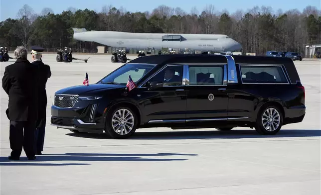 The hearse carrying the flag-draped casket of former President Jimmy Carter arrives at Dobbins Air Reserve Base in Marietta, Ga., Tuesday, Jan. 7, 2025. Carter died Dec. 29 at the age of 100. (AP Photo/Alex Brandon, Pool)